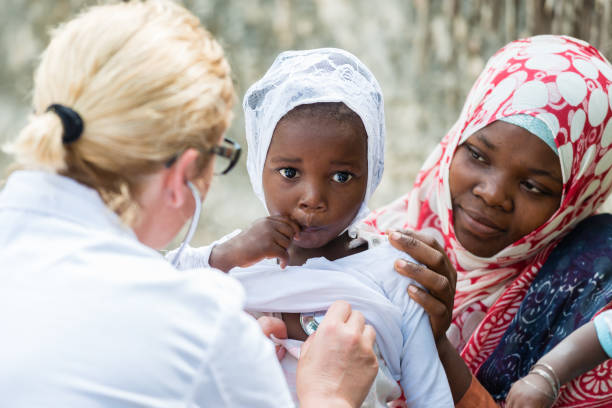 стетоскоп экзамен африканской маленькой девочки - malaria стоковые фото и изображения