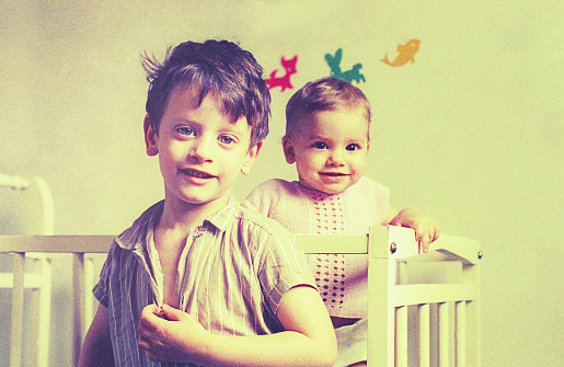 Vintage photo from the seventies ofa sleepy brothers smiling to camera.