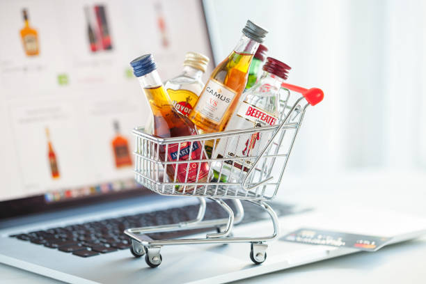 Minsk, Belarus - January 16, 2018: Illustrative editorial photo of mini shopping cart full of small alcohol bottles -  Camus and Martell cognacs, Havana club rum, Beefeater gin on laptop background. Minsk, Belarus. Minsk, Belarus - January 16, 2018: Illustrative editorial photo of mini shopping cart full of small alcohol bottles -  Camus and Martell cognacs, Havana club rum, Beefeater gin on laptop background. Minsk, Belarus. njemp tribe stock pictures, royalty-free photos & images