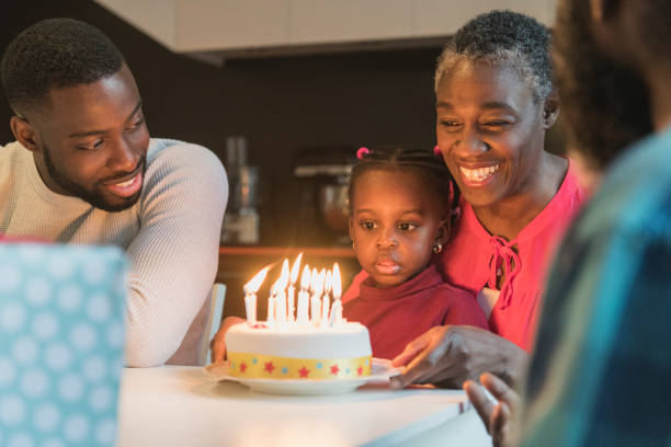 誕生日ケーキとラップが見つめている上に座っての孫娘祖母 - birthday family party cake ストックフォトと画像