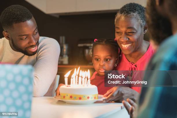 Grandmother With Birthday Cake And Granddaughter Sitting On Lap Staring Stock Photo - Download Image Now