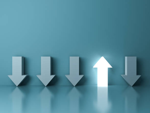 Stand out from the crowd and different concept , One glowing light up arrow among other down arrows on green pastel color background with reflections and shadows