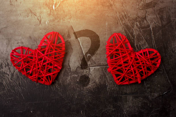 istock Two hearts with a question mark on a dark background. Theme for St. Valentine's Day 911787908