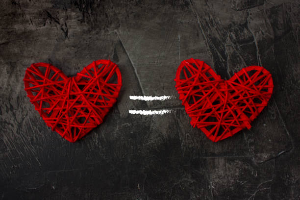 istock Two hearts with the equal sign on a dark background. Theme for St. Valentine's Day 911787922