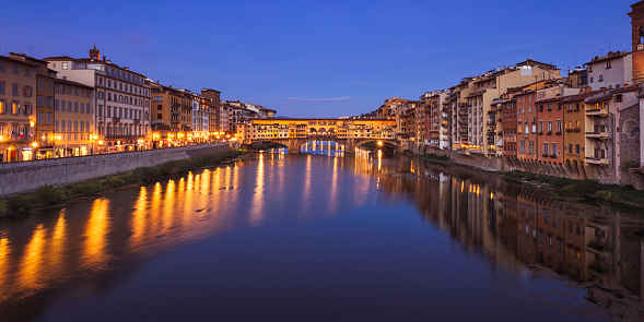 Houses along Arno river, and the medieval Ponte Vecchio bridge crossing the river in Florence, Italy.