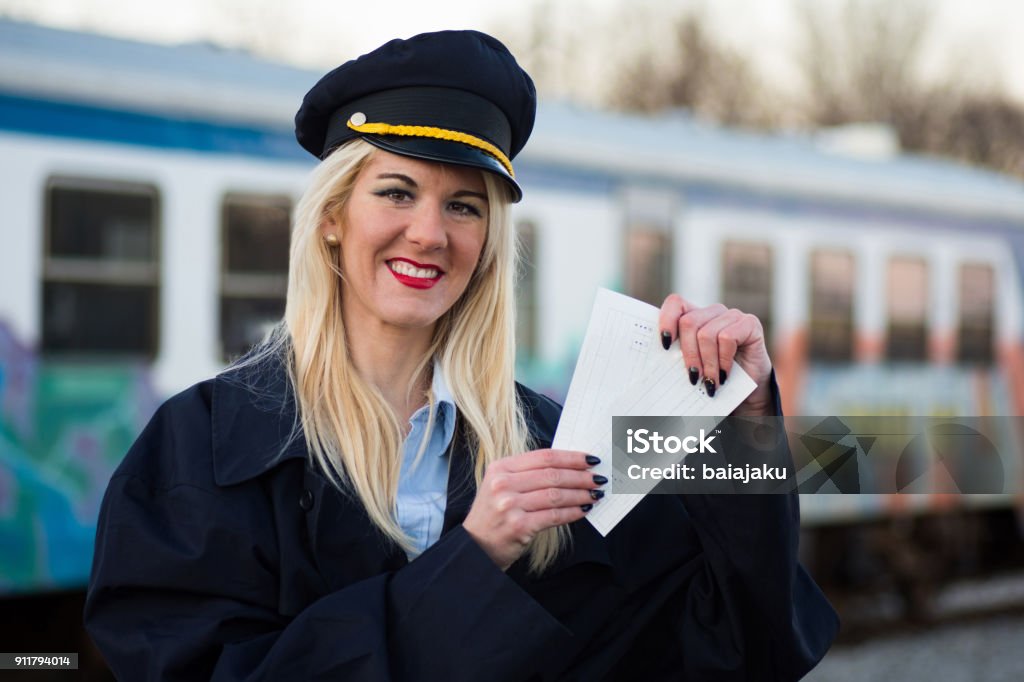 railway worker with tickets The smiling female railway worker or railroad employee is showing the tickets outdoors on railway station. Train - Vehicle Stock Photo