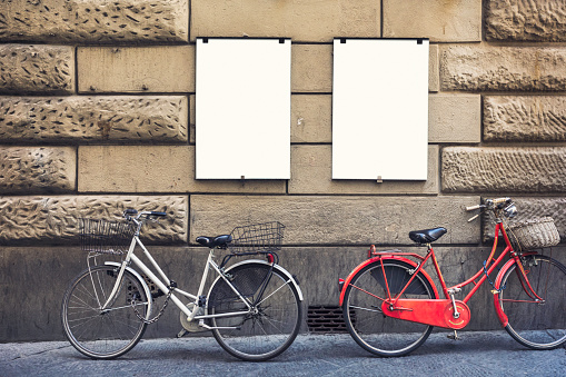Two blank posters on a city building wall, with two bikes parked in front.