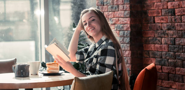 Beautiful girl reads a book in a cafe