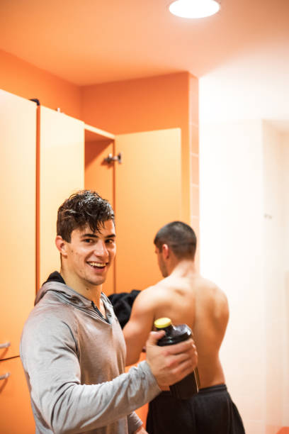 istock Young Man Shaking a Protein Shake in Locker Room after Training in Gym 911803260
