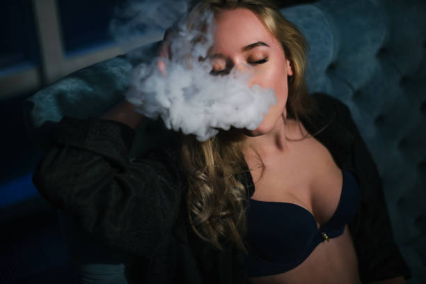 istock Beautiful woman is vaping. Dark background. Studio shooting. 911811388