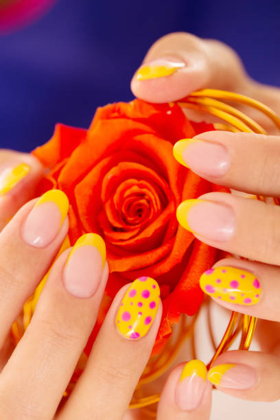 Nails Polished in Yellow Holding a Red Rose Close-Up