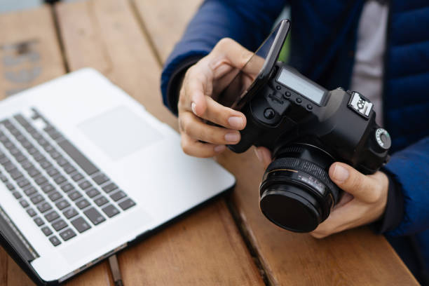 istock Young Man Uses Wireless Connection Between Photo Camera And Smart Phone 911812102