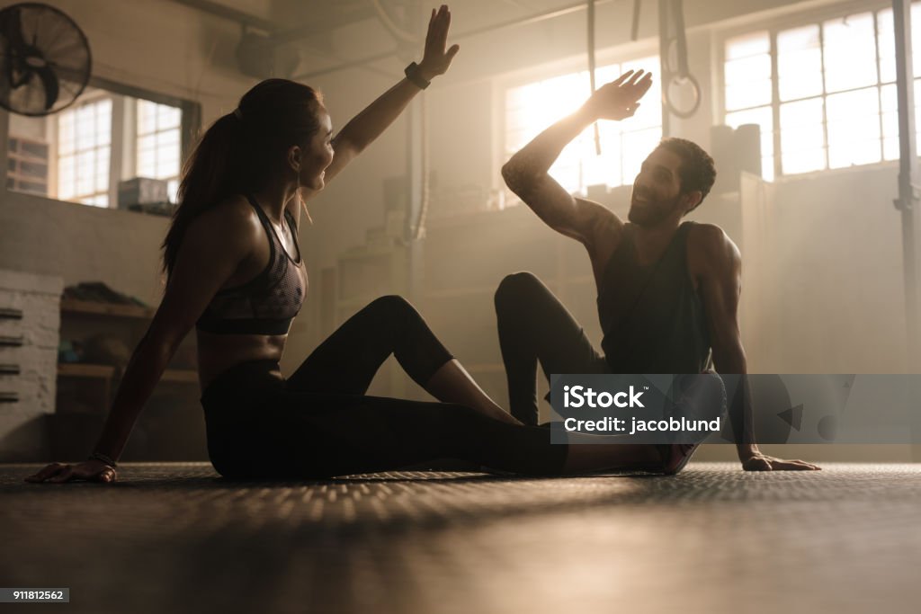 Fit couple high five after workout in health club Fitness man and woman giving each other a high five after the training session in gym. Fit couple high five after workout in health club. Gym Stock Photo