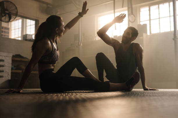 Fit couple high five after workout in health club Fitness man and woman giving each other a high five after the training session in gym. Fit couple high five after workout in health club. cross training stock pictures, royalty-free photos & images