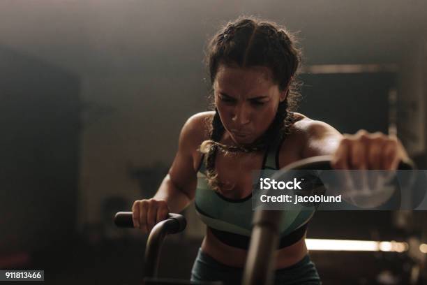 Woman Exercising Hard On Gym Bike Stock Photo - Download Image Now - Effort, Exercising, Dark