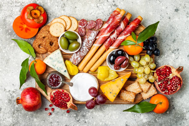 istock Appetizers table with antipasti snacks. Cheese and meat variety board over grey concrete background. Top view, flat lay 911813710