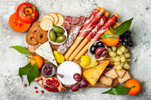 Appetizers table with antipasti snacks. Cheese and meat variety board over grey concrete background. Top view, flat lay Appetizers table with antipasti snacks. Cheese and meat variety board over grey concrete background. Top view, flat lay pomegranate in spanish stock pictures, royalty-free photos & images