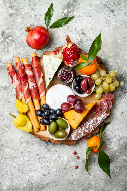 Appetizers table with antipasti snacks. Cheese and meat variety board over grey concrete background. Top view, flat lay Appetizers table with antipasti snacks. Cheese and meat variety board over grey concrete background. Top view, flat lay, copy space pomegranate in spanish stock pictures, royalty-free photos & images