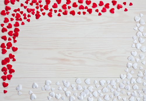 White and red heart symbols on a white wooden background. Top view, background. Concept for wedding, engagement, valentine's day and other romantic holidays and events