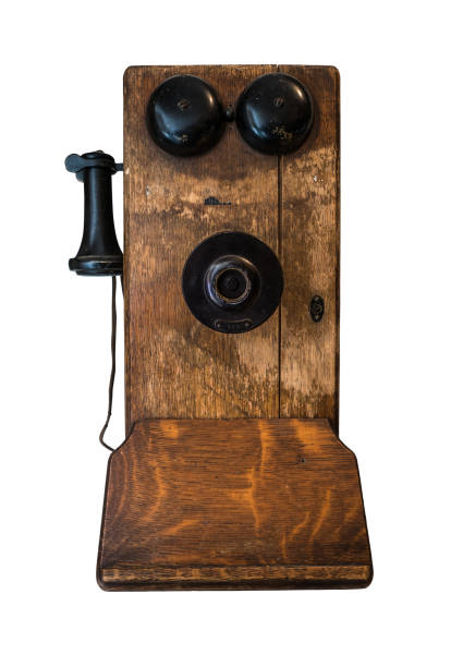 An old rotary dial phone hangs on the wall covered in faded flower wallpaper.