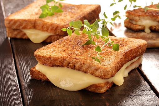 Fresh toast with cheese and herbs on wooden background