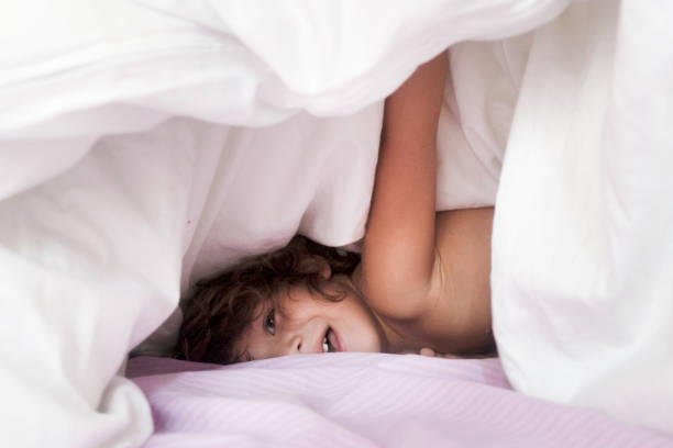 istock Happy little boy under the duvet playing. 911824452