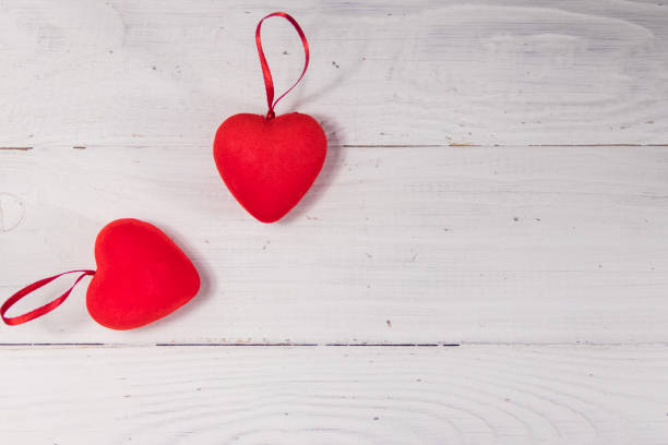 istock Two red hearts on white wooden background 911834112