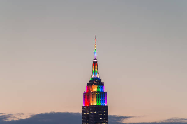 A close-up of the Empire State Building displaying Pride colors taken from Brooklyn just after sunset.