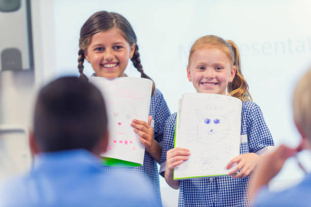 istock Schoolgirls giving a presentation in school uniform. 911839524