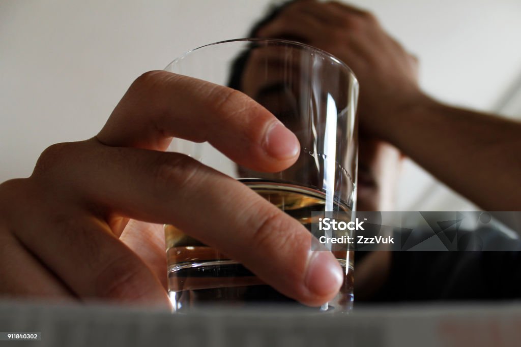Poison Drunk young adult male holding glass of alcohol, studio shot. Alcohol - Drink Stock Photo