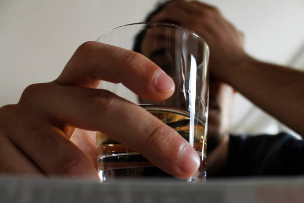 Poison Drunk young adult male holding glass of alcohol, studio shot. substance abuse stock pictures, royalty-free photos & images