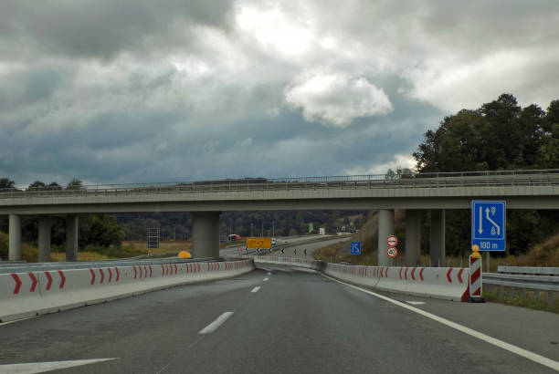 istock Exit from the highway with overpass and many various road signs: Overtaking prohibited and Speed limit 911849542