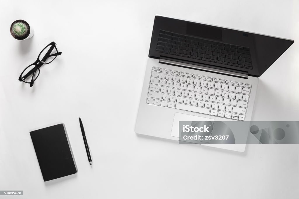 Stylish minimalistic desk table with laptop, cactus, eyeglasses, notebook and pen. Workspace of bloggers, students, freelancers Stylish minimalistic desk table with laptop, cactus, eyeglasses, notebook and pen. Workspace of bloggers, students and freelancers. Top - Garment Stock Photo