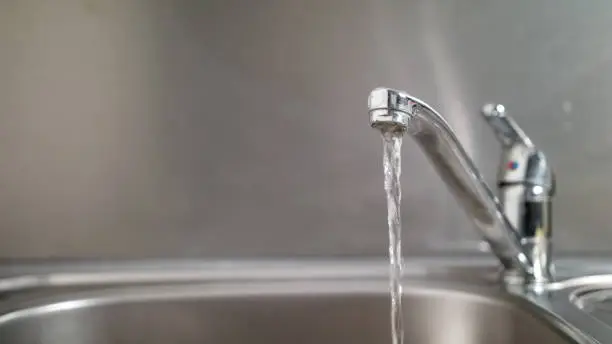 Water running from a tap into a sink. Close-up shot