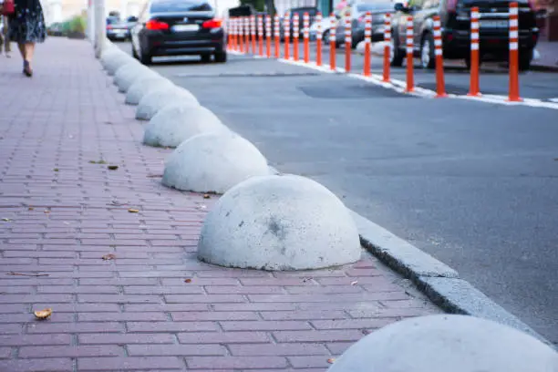 Car or motor vehicle stop security barriers or hemispheres bollards. Concrete structures to prevent parking on the sidewalks are placed at the edge of the roadway for cars