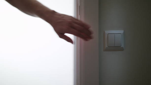 istock A Hand Switching On the Light in a Dark Room 911855264