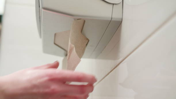 Hand Picking a Paper Towel A hand picking a paper towel in the bathroom. Close-up shot paper dispenser stock pictures, royalty-free photos & images