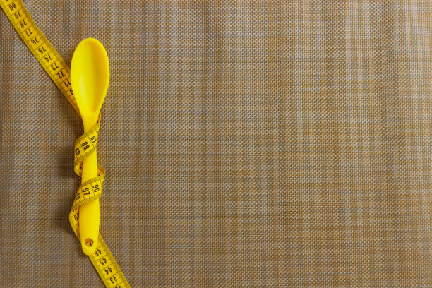 spoon tied with tape measure. diet concept stock photo