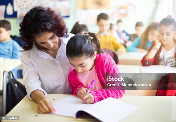 Teacher Teaches To Write To The Girl Student In The Class Stock Photo - Download Image Now