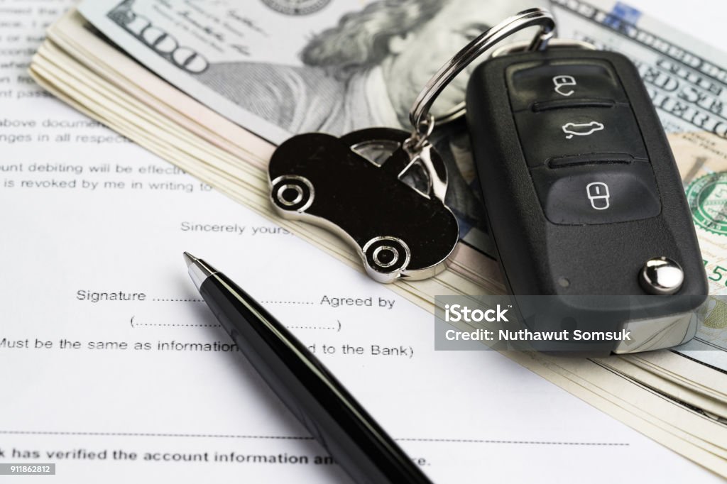 Buy or sell car, purchase or rent automobile service with key with car keychain on pile of US Dollar banknotes money on printed contract paper and pen to sign, finance installment or debt awareness Buy or sell car, purchase or rent automobile service with key with car keychain on pile of US Dollar banknotes money on printed contract paper and pen to sign, finance installment or debt awareness. Car Stock Photo