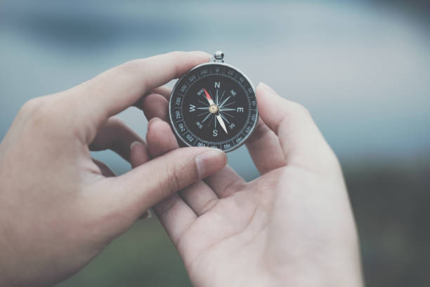 istock hand holding compass for searching direction outdoor. man seeking way with nature background. travel lifestyle, summer vacation concept 911863974