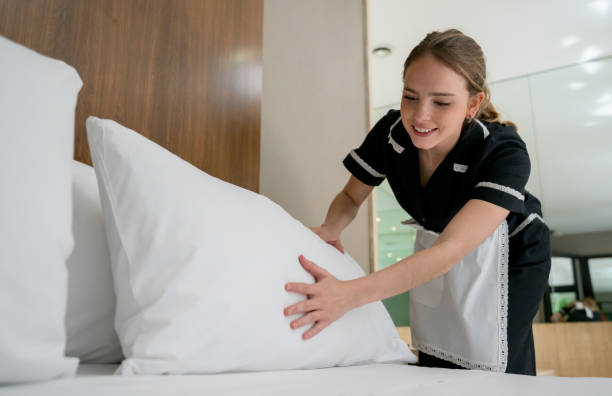 housekeeper making the bed at a hotel looking happy - hotel occupation imagens e fotografias de stock