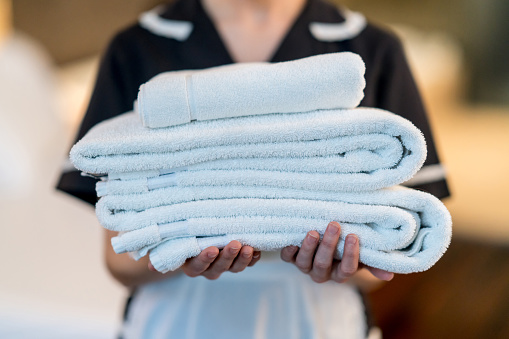 Stack of white bed sheets in an industrial laundry. Cleaning service for hotels, clinics, hospitals. Selective focus.