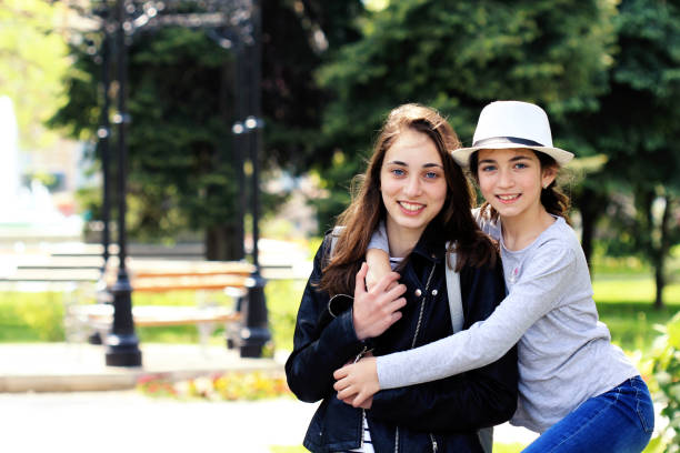 istock Two beautiful sisters embrace each other with spread smiles. 911864156
