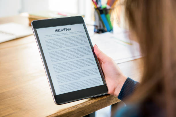 student reading e-book reader at the table - kindle e reader book reading imagens e fotografias de stock