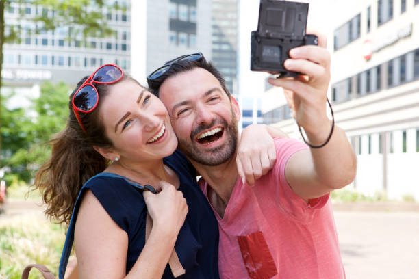 istock Close up laughing couple taking self portrait outside with camera 911864938