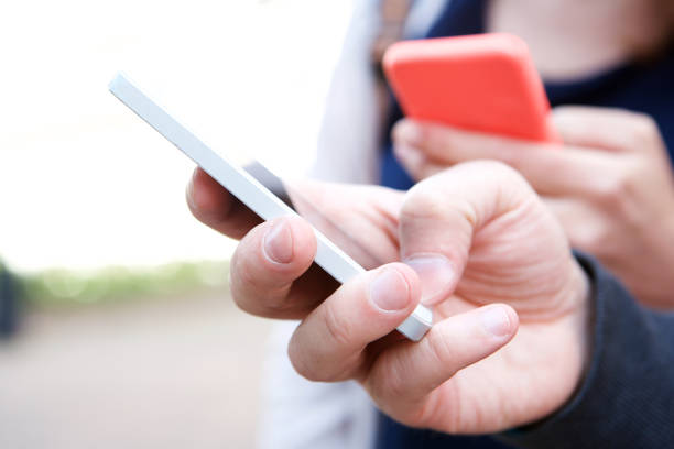 istock Close up two people holding mobile phones in hands 911864970