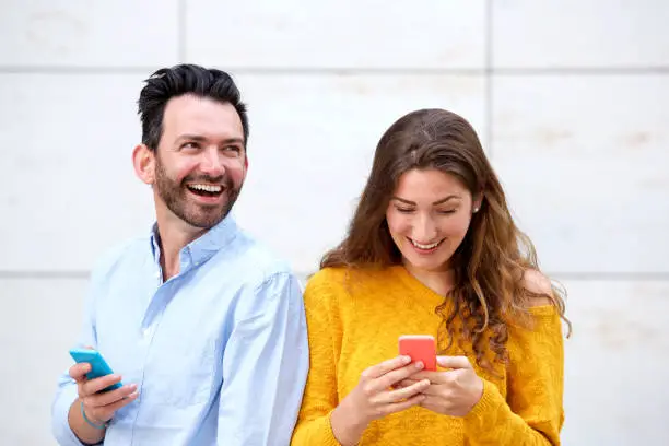 Close up portrait of happy man and woman holding cellphones and laughing