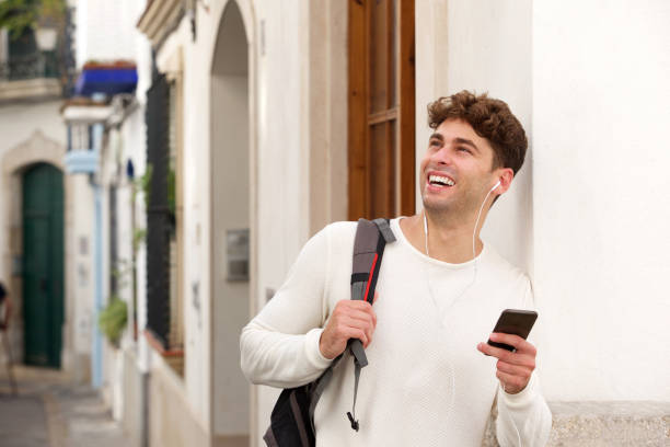 istock Smiling man holding cellphone with backpack and headphones 911867170