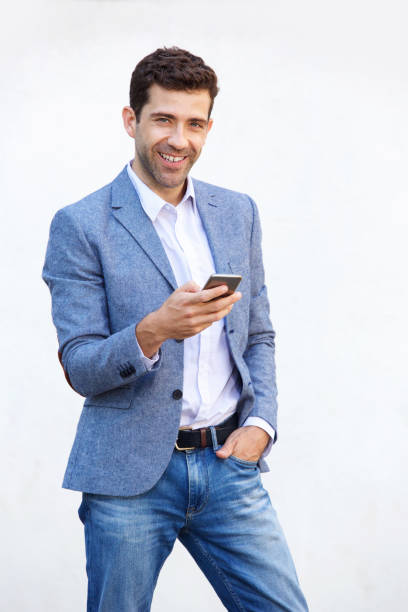 istock Handsome young man with smart phone standing against white background 911867346